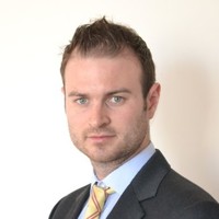 A man in a suit and tie with a neutral expression.